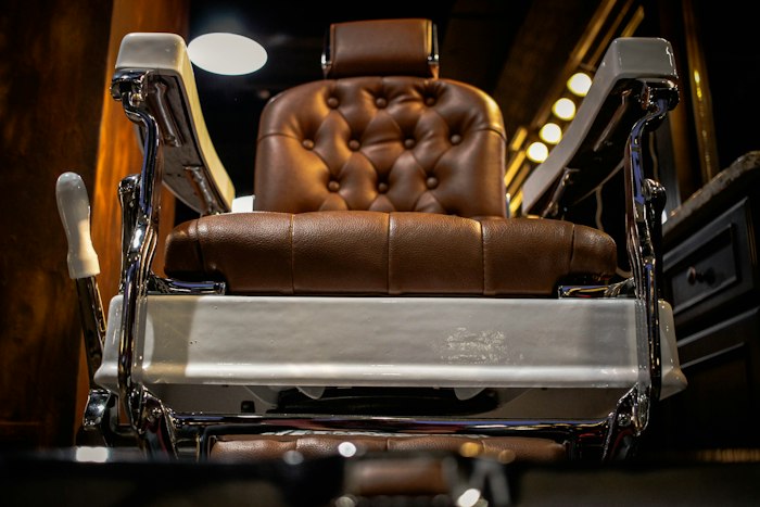 A cognac tufted-leather barber chair with a polished chrome frame